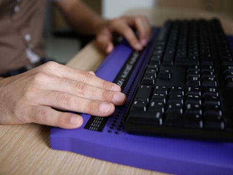Person mit Händen an der Computertastatur mit Braillezeile