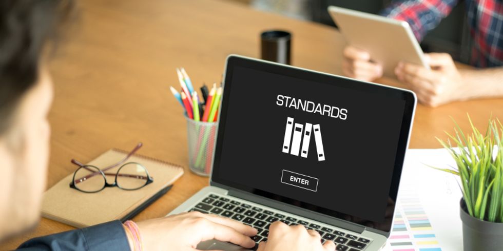 Hände am Laptop, auf dem Bildschirm stehen die Worte Standards und Enter