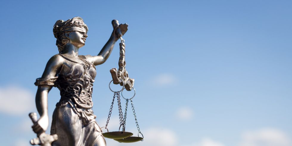 Justitia-Figur aus Metall vor blauem Himmel