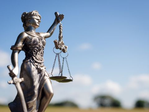Justitia-Figur aus Metall vor blauem Himmel