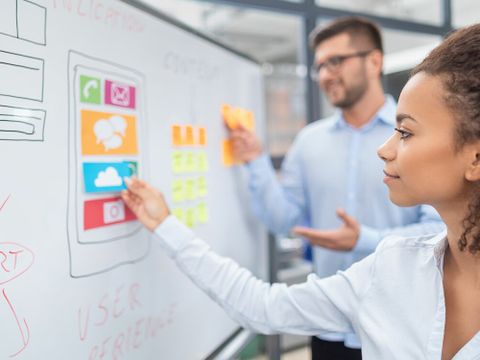 Junge Frau und Mann beim Brainstorming an einem Whiteboard